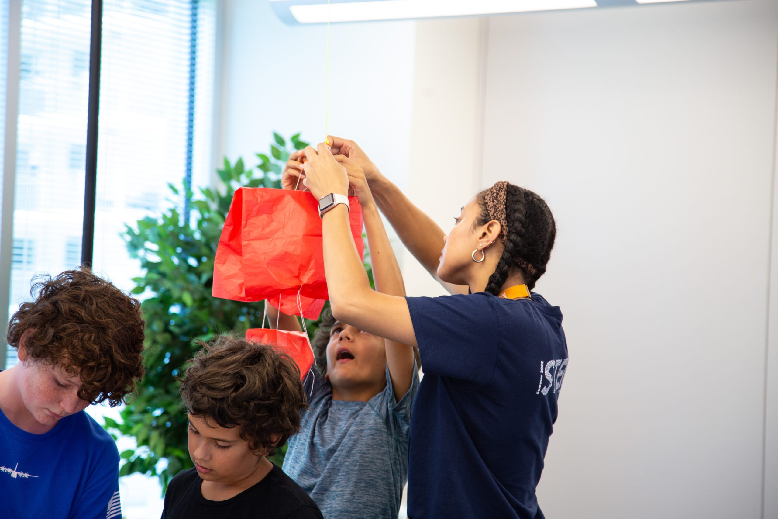Photo of a STEM communicator working with students in a parachute experiment