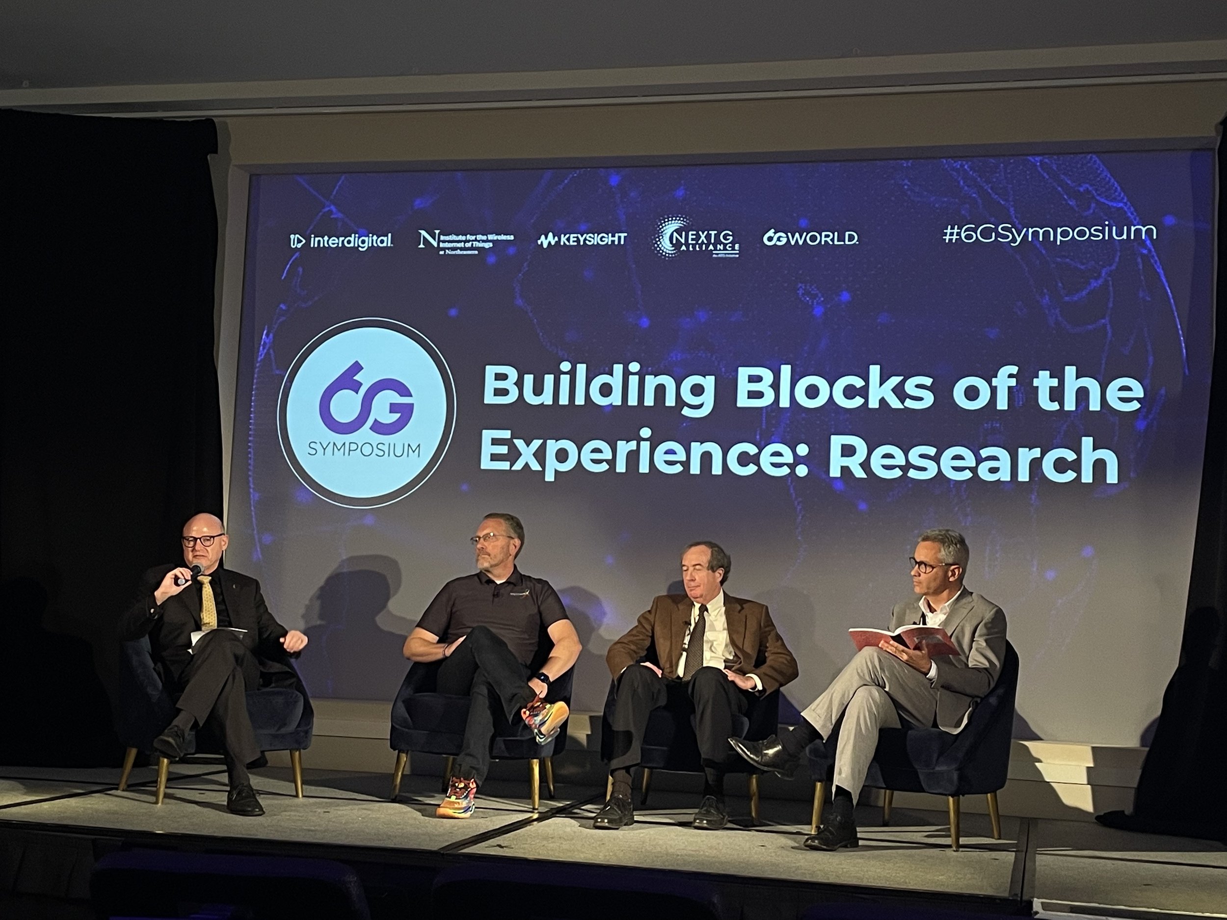 Photo of panelists on a stage giving a talk about 6G Building Blocks of the Experience: Research